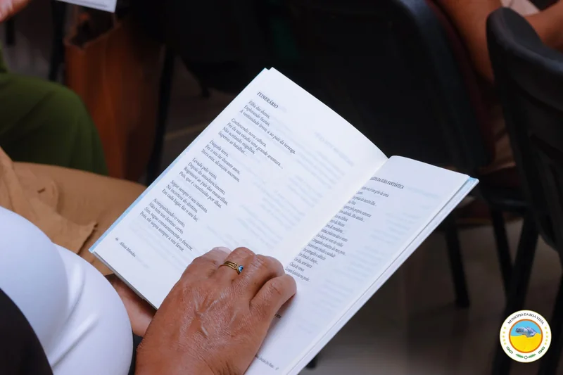 Livro aberto no poema Itinerário, lido por uma leitora durante o evento